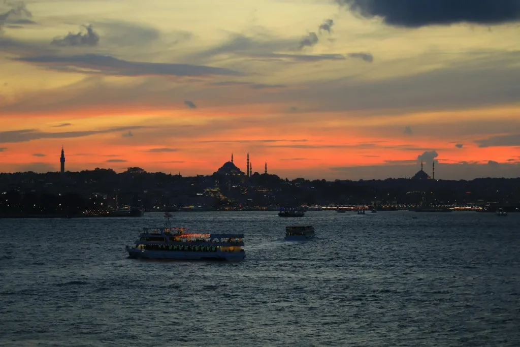 Bateaux de croisiere sur le Bosphore au coucher du soleil avec skyline d'Istanbul, mosquees et minarets en silhouette