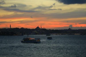 Bateaux de croisiere sur le Bosphore au coucher du soleil avec skyline d'Istanbul, mosquees et minarets en silhouette