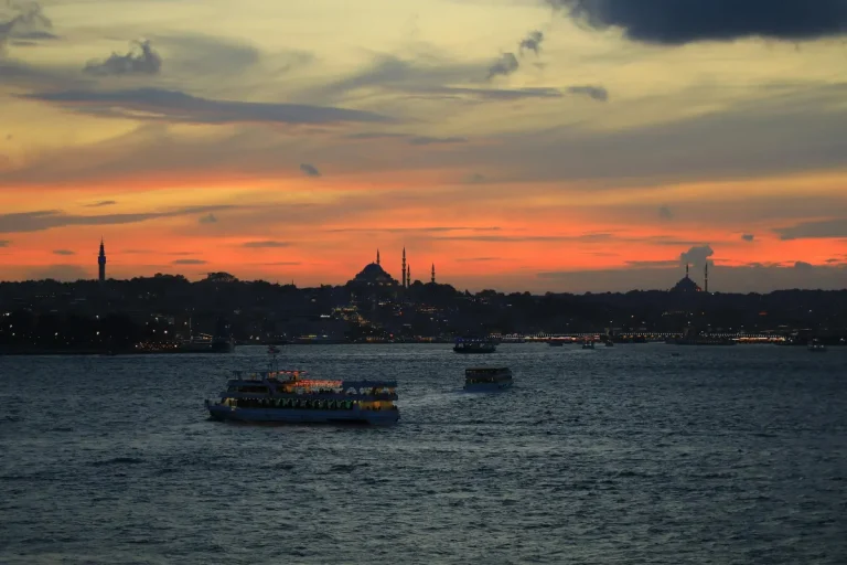 Bateaux de croisiere sur le Bosphore au coucher du soleil avec skyline d'Istanbul, mosquees et minarets en silhouette