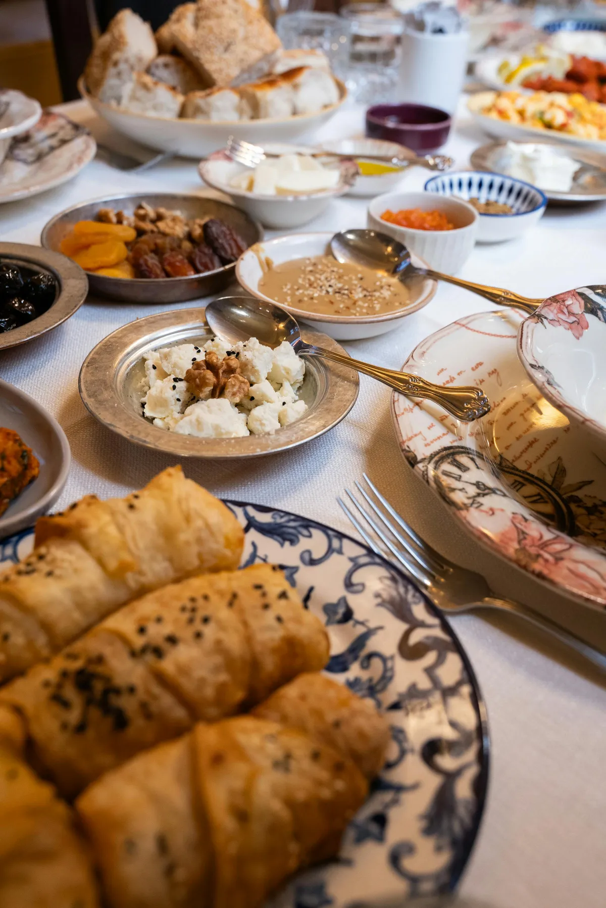 Table de kahvaltı turc avec börek au sésame, mezze, fromages, pâtes de tomate et confitures sur vaisselle ottomane