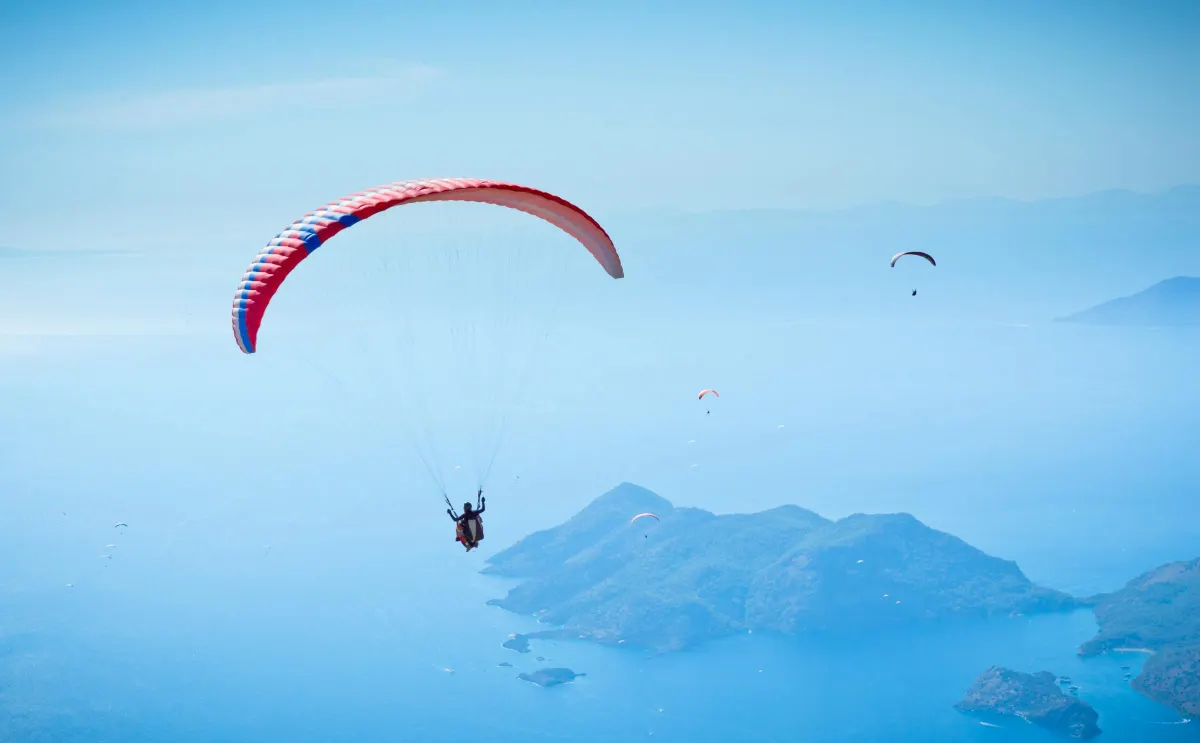 Parapente biplace en vol au-dessus du lagon d'Ölüdeniz, décollage depuis le mont Babadağ, mer Méditerranée en arrière-plan