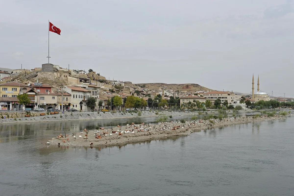 Ville etagee au bord d'un large fleuve, banc de sable seme de poteries en terre cuite