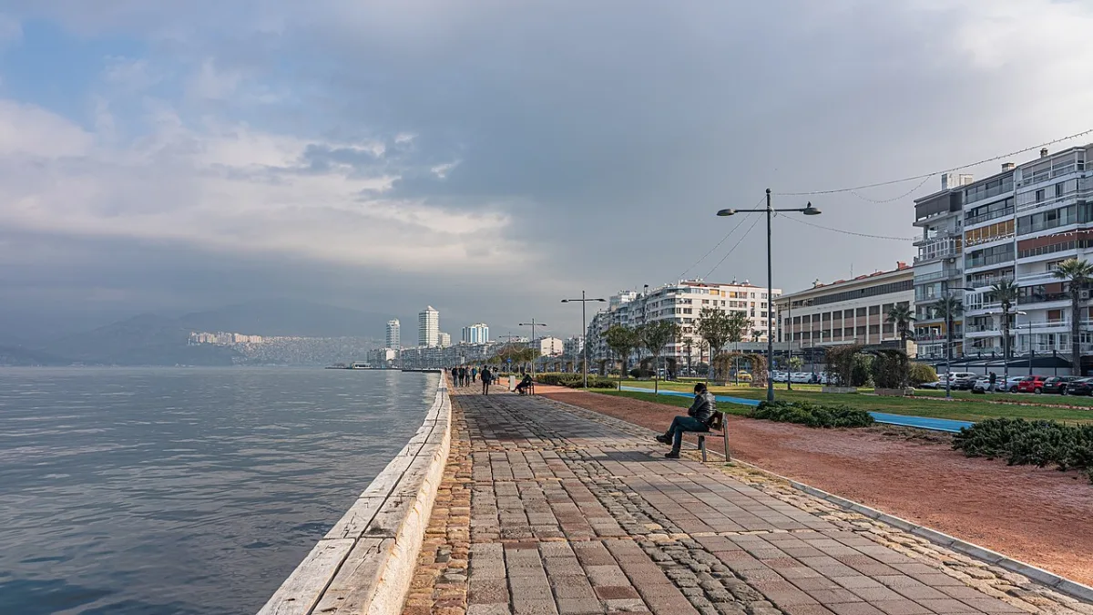 Promenade pavée au bord du golfe, pelouse et bancs, immeubles alignés face a la mer