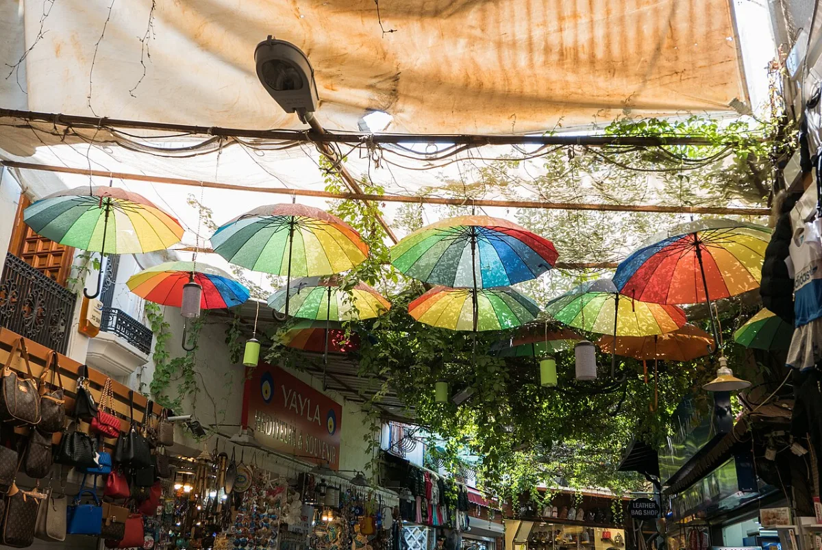 Parasols multicolores suspendus au-dessus d'une ruelle commercante bordée de boutiques