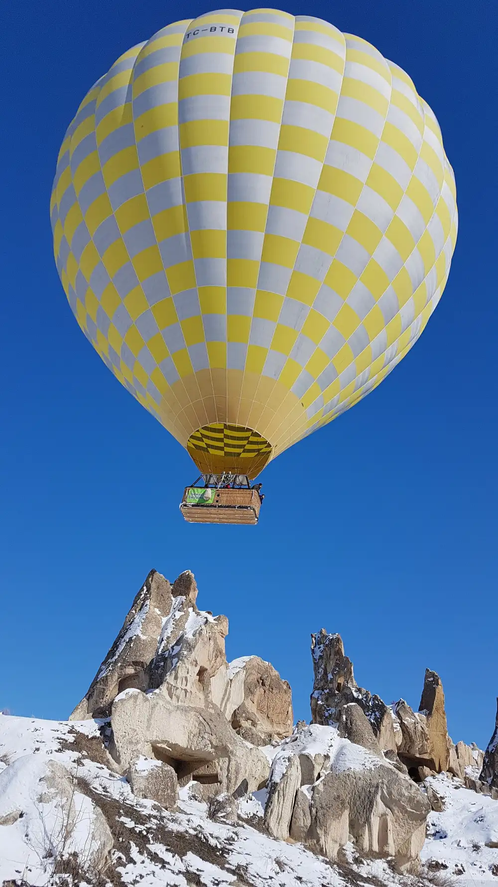 Montgolfière survolant les cheminées de fées enneigées de Cappadoce