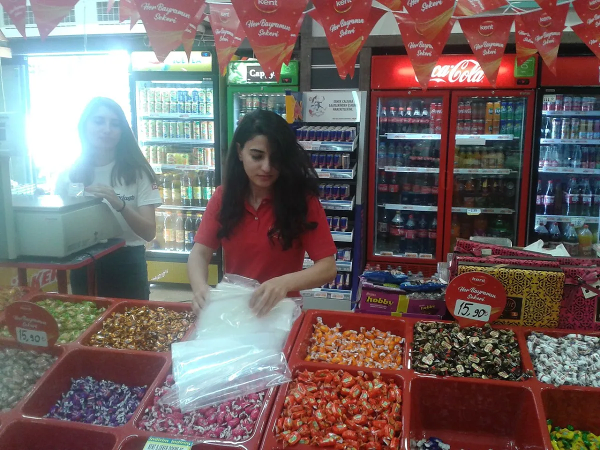Étal de confiseries en vrac dans un supermarché turc sous des fanions rouges de bayram
