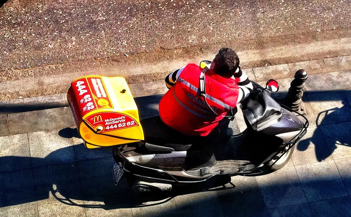 Livreur à scooter vu de dessus dans une rue d'Istanbul, gros top-case de livraison fixé à l'arrière
