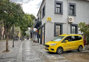 Taxi jaune turc stationné sur un large trottoir pavé bordé de palmiers à Antalya, plaque 07 T 2826
